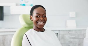 Woman smiling happily in the dentist chair after receiving her full mouth restoration.