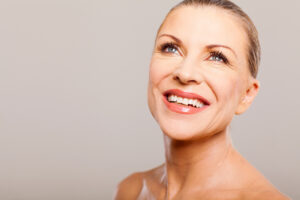 Older woman smiling broadly to show off her new smile after smile makeover treatment