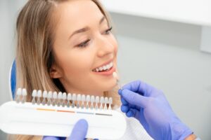 Woman happily having her teeth color-matched for dental veneers.